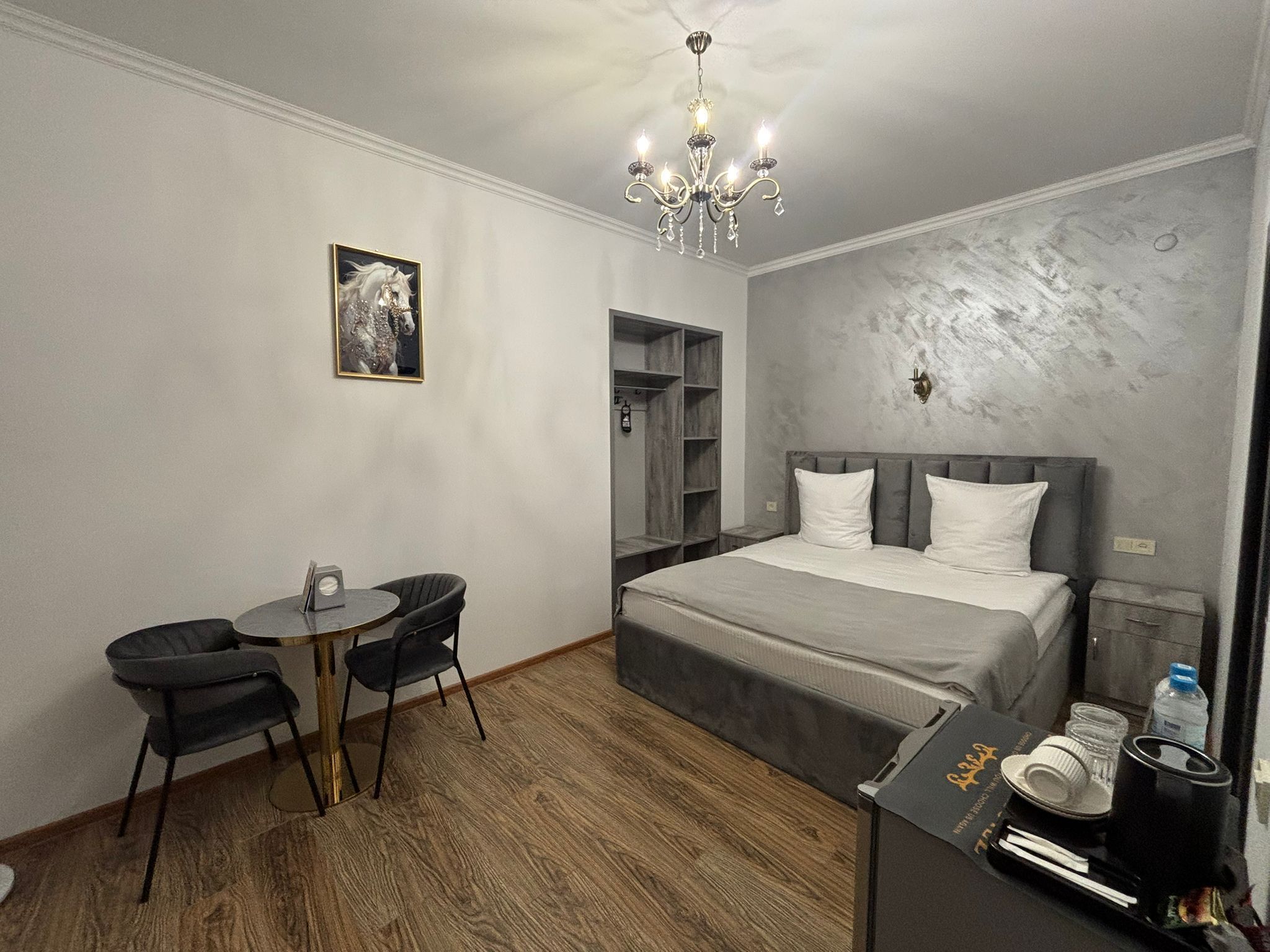 Una habitación de hotel moderna con una cama, un escritorio con una silla, una araña y un armario.