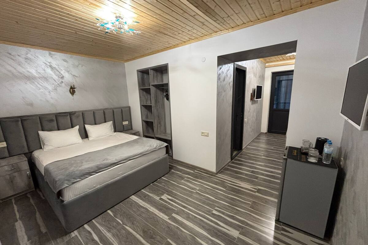 A modern bedroom with a large bed, built-in shelving, a wardrobe, and a ceiling fan.