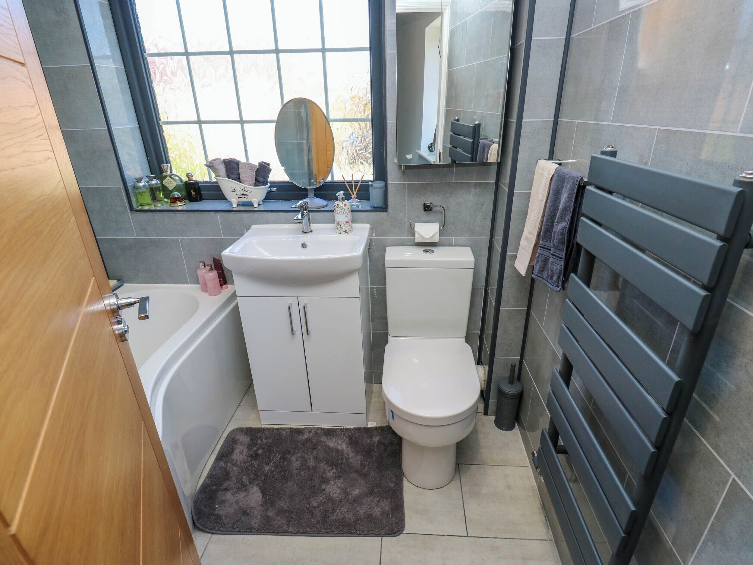 Ein Badezimmer mit einer Badewanne, einem Waschbecken, einer Toilette und einem Fenster mit Blick nach draußen.