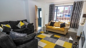 Un salon avec deux canapés, dont un jaune, et un tapis à motifs.