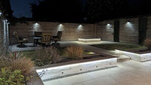 Un espace extérieur bien éclairé, aménagé avec une terrasse et un foyer intégré.