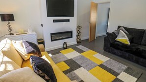 Un salon moderne avec un canapé, un divan en cuir noir et un grand téléviseur fixé au mur.