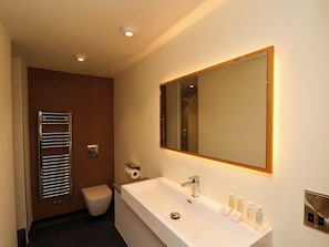 A modern bathroom with a white sink, a large mirror, and a towel rack. - Apartment 1 (Scarborough)