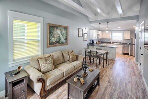 A spacious living room with a sofa, coffee table, and artwork on the wall.