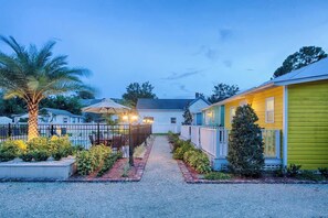 A pathway leading to a yellow building with a covered outdoor seating area and a palm tree. - Historic Bungalow w/ Hot Tub, Walk to St. George (St. Augustine)