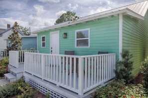A single-story house with a green exterior, a white front door, and a white porch with railings. - Historic Bungalow w/ Hot Tub, Walk to St. George (St. Augustine)