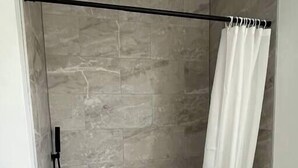 A modern bathroom with a freestanding bathtub, a showerhead, and a curtain. - The Royal Union w/ king & queen bed (Calumet Township)