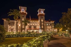 A large, historic building with two prominent towers, a well-maintained garden with string lights, and an American flag. - Historic St. Augustine Bungalow: Walk to Sites & (St. Augustine)