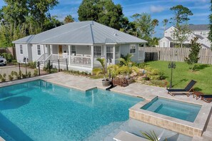 A house with a swimming pool, a fenced backyard, and a wooden deck.