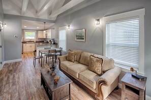 A spacious living area with a sofa, coffee table, and dining table. A kitchen is visible in the background. - Historic St. Augustine Bungalow w/ Hot Tub & (St. Augustine)
