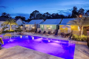 A pool area with lounge chairs and a small patio.