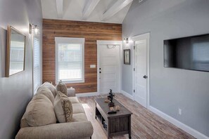 A modern living room with a sofa, coffee table, and a TV mounted on the wall.