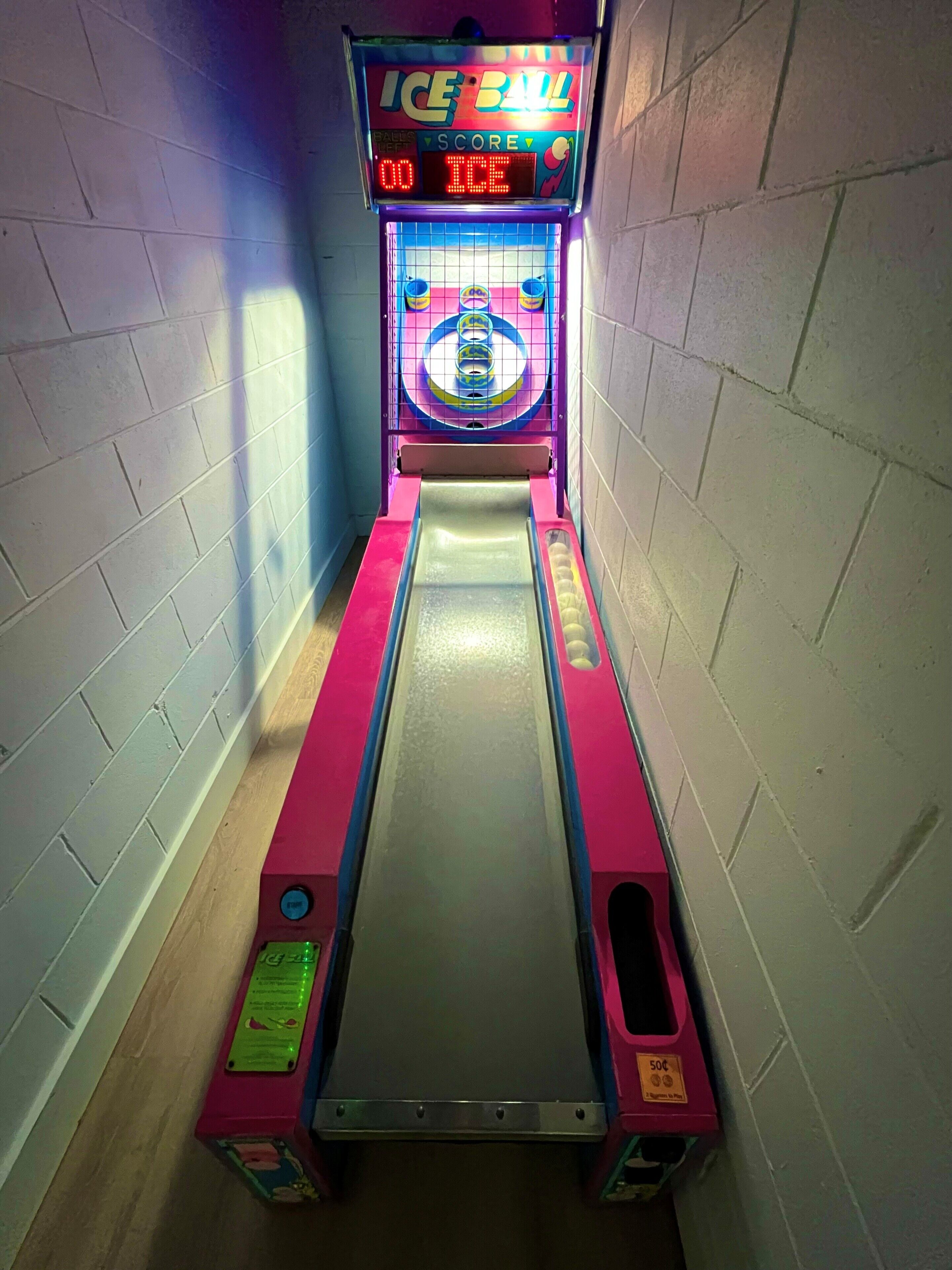 Un pasillo estrecho y bien iluminado con un juego de arcade llamado 