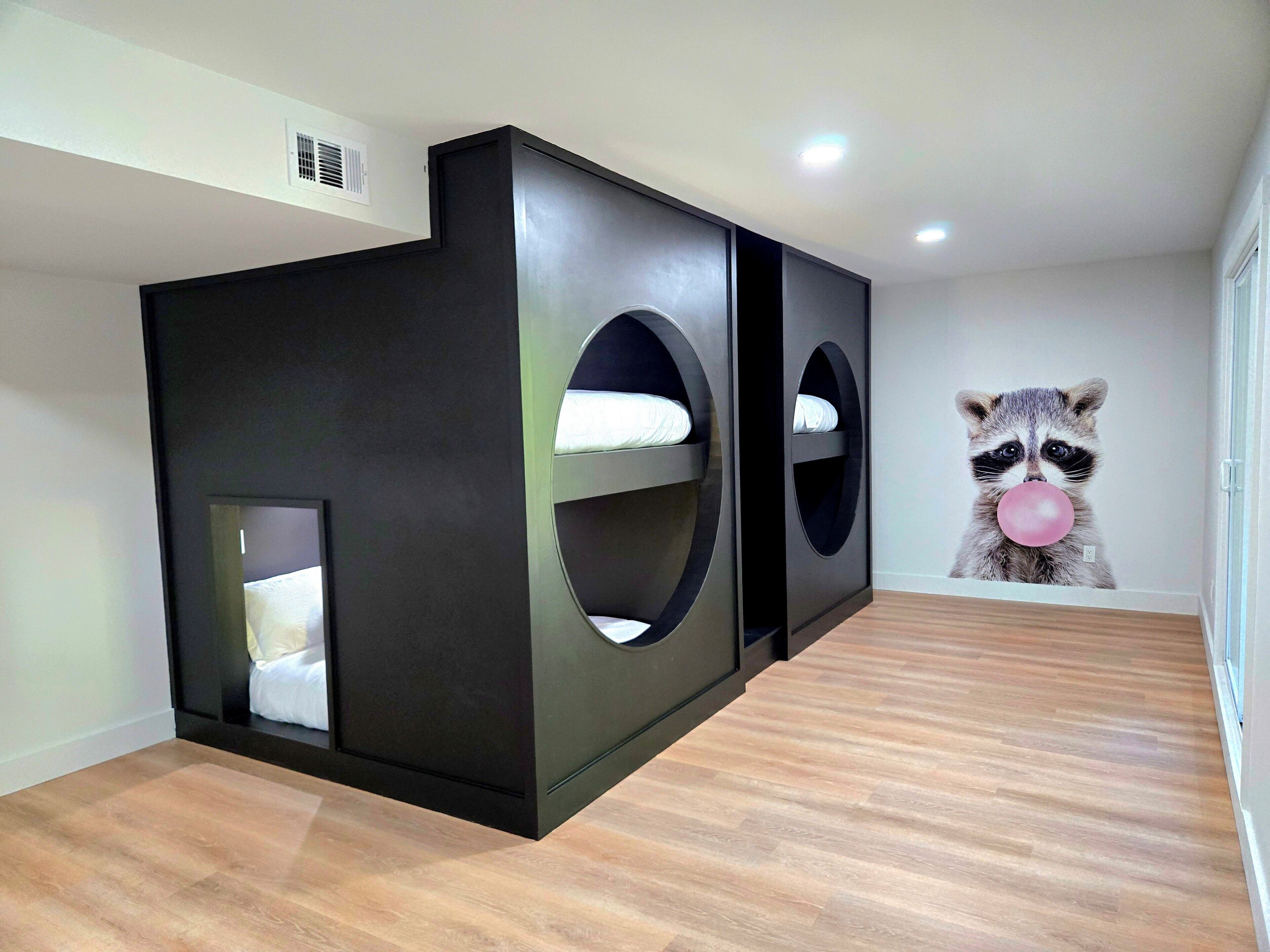 Habitación moderna con literas e ilustración de un mapache en la pared.