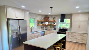 A modern kitchen with a large island, stainless steel appliances, and light wood flooring.