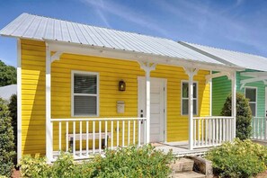 A yellow house with a white porch and a white door.