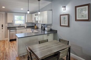 A modern kitchen with white cabinets, a wooden dining table, and a small island.