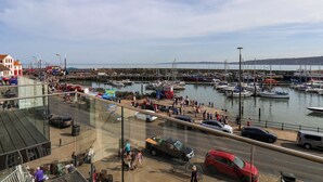 A marina with boats docked, a pedestrian walkway, and a road with cars. - Apartment 2 (Scarborough)