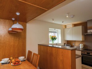 A modern kitchen with wooden cabinetry, a central island, and a dining area with a wooden table and chairs. - Apartment 2 (Scarborough)