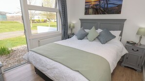 A bedroom with a large bed, a nightstand, a lamp, and a painting on the wall.