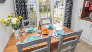 A dining table set with teal plates, a vase of yellow flowers, and a bottle of red wine.