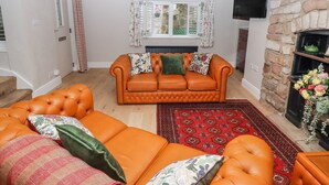 Un salon avec un canapé, un tapis à motifs, une cheminée en pierre et un téléviseur fixé au mur.