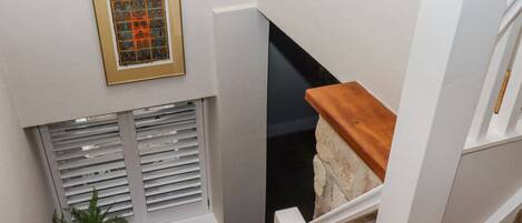 A staircase with white railings, a wooden handrail, and a stone accent wall.