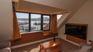 A modern living room with a large window, a flat-screen TV, and a wooden coffee table. - Apartment 3 (Scarborough)