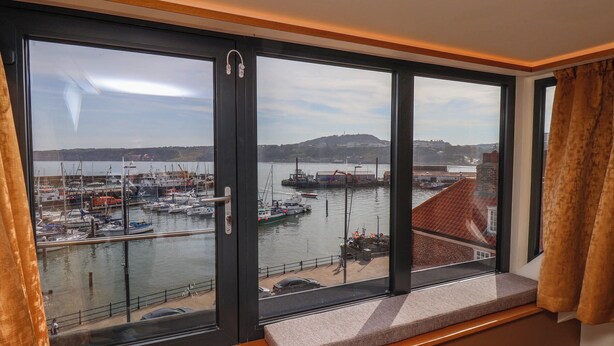 A large window with a view of a marina, a bench, and a door with a handle. - Apartment 3 (Scarborough)