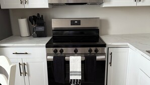 A kitchen with white cabinets, a stainless steel stove, and a microwave.
