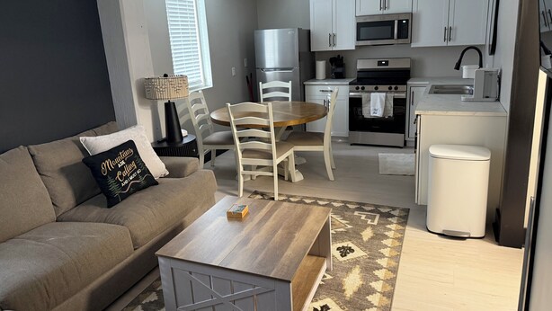 A modern living room with a sofa, coffee table, and dining area.