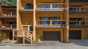 A multi-story building with a garage, a covered outdoor area, and a staircase leading to the upper levels.