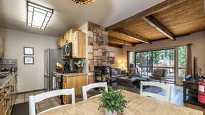 A spacious kitchen with wooden cabinets, a stone accent wall, and a dining area with a table and chairs.