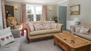 A cozy living room with a beige sofa, a wooden coffee table, and floral curtains.
