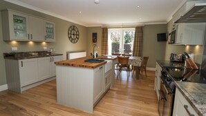A modern kitchen with wooden flooring, white cabinetry, and a central island.