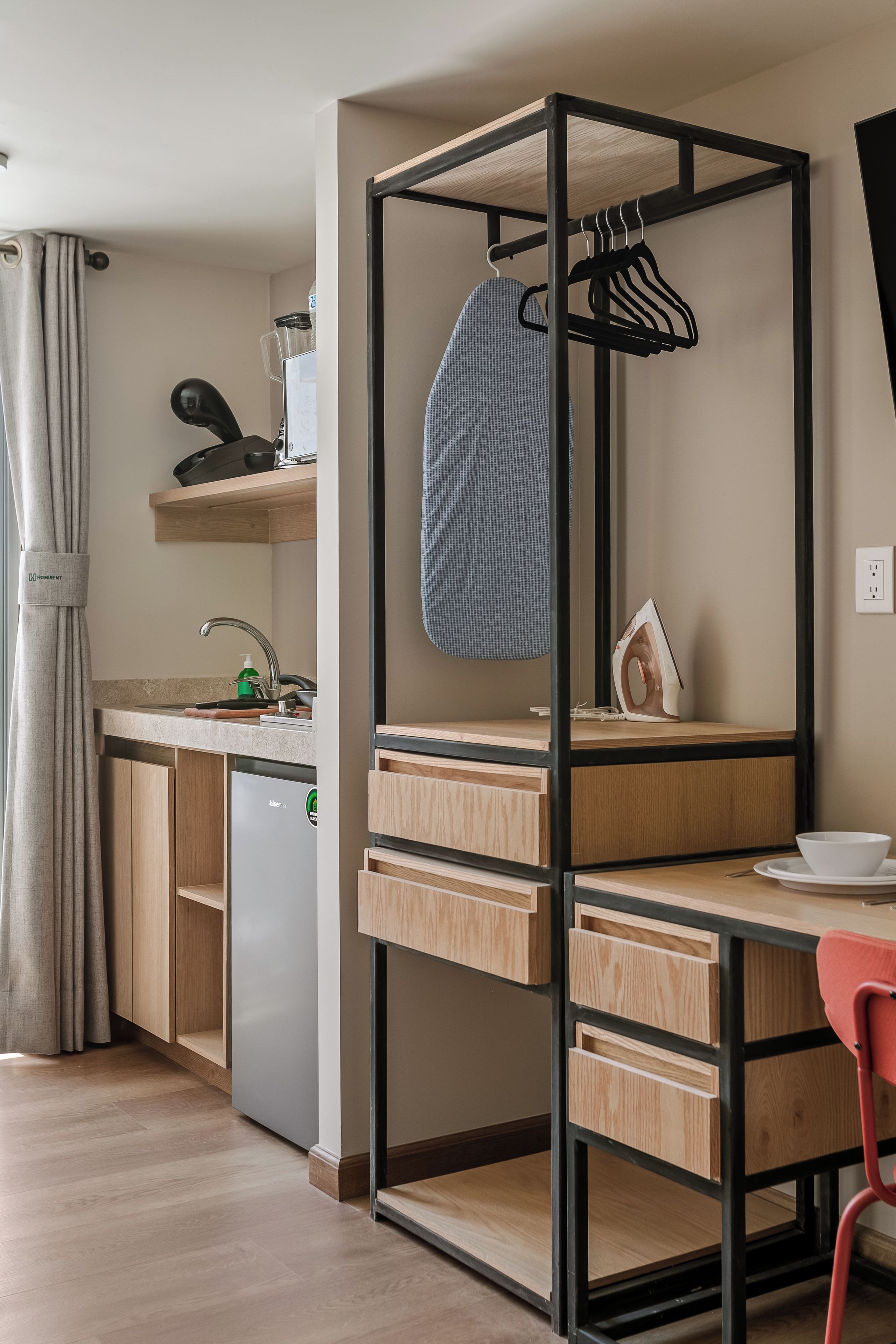 A compact kitchen with a foldable desk, a built-in dishwasher, and a compact refrigerator.