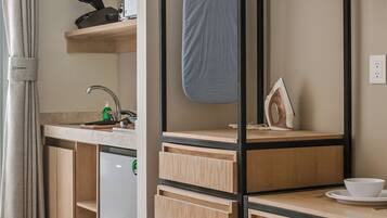 A compact kitchen with a foldable desk, a built-in dishwasher, and a compact refrigerator.