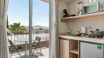 Une cuisine compacte avec vue sur la ville, un coin repas avec des chaises et un petit réfrigérateur.