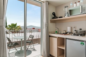 Une cuisine compacte avec vue sur la ville, un coin repas avec des chaises et un petit réfrigérateur.