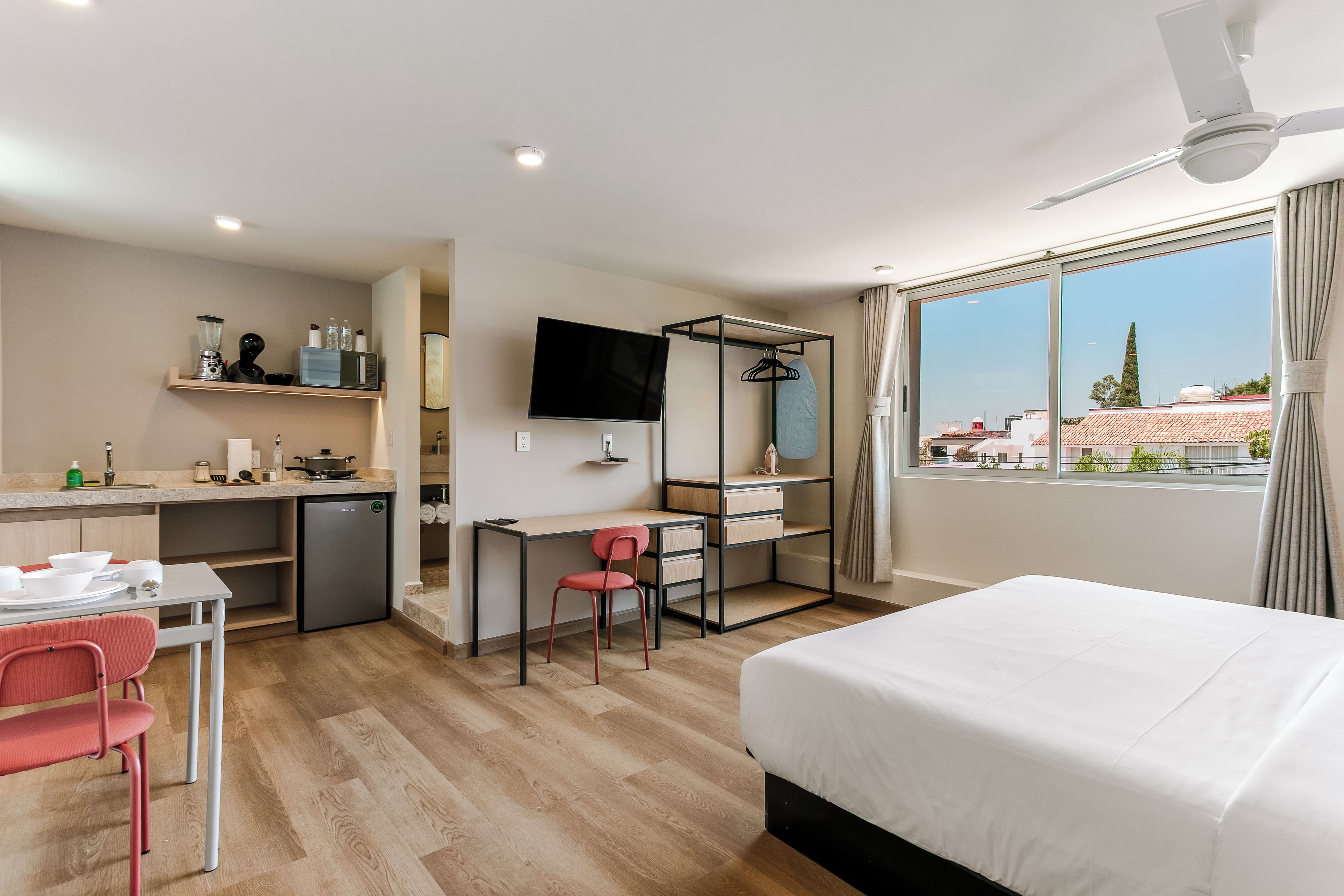Une chambre d’hôtel avec un lit, un bureau, une chaise, une télévision et un balcon avec vue.