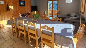 Un comedor con una larga mesa, sillas de madera y una araña.