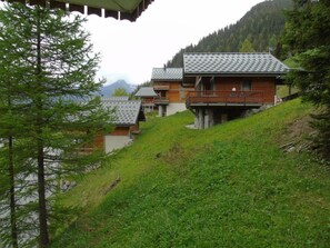 A hillside property with multiple buildings, including a prominent wooden structure with a balcony. - 4th floor, view mountain, terrace, balcony, tv, ski locker, 36m², Valfréjus (Valfréjus)