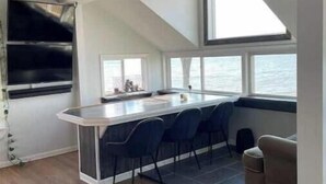 A modern kitchen with a bar area, large windows, and a view of the sea. - Lakefront Home Huron/Vermillion Amazing View (Vermilion)