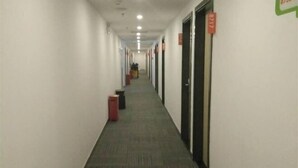 A long, narrow hotel corridor with doors on both sides, numbered signs, and a carpeted floor. - Xiaomei Hotel (Beijing Universal Studios Tuqiao Subway Station) (Beijing)