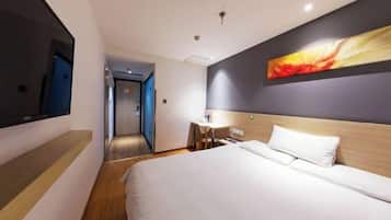 Una camera d'albergo con un letto, una scrivania, una sedia, una televisione e un quadro appeso al muro.