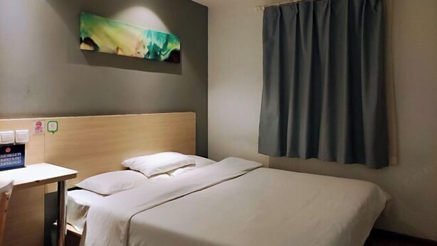A hotel room with a bed, a desk, a wall-mounted artwork, and a window with curtains. - Xiaomei Hotel (Beijing Universal Studios Tuqiao Subway Station) (Beijing)