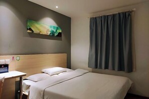 A hotel room with a bed, a desk, a wall-mounted artwork, and a window with curtains. - Xiaomei Hotel (Beijing Universal Studios Tuqiao Subway Station) (Beijing)