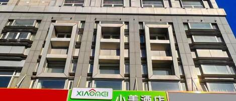 A building with multiple windows and a sign for 'XIAONGLI' and '小美酒店'.
