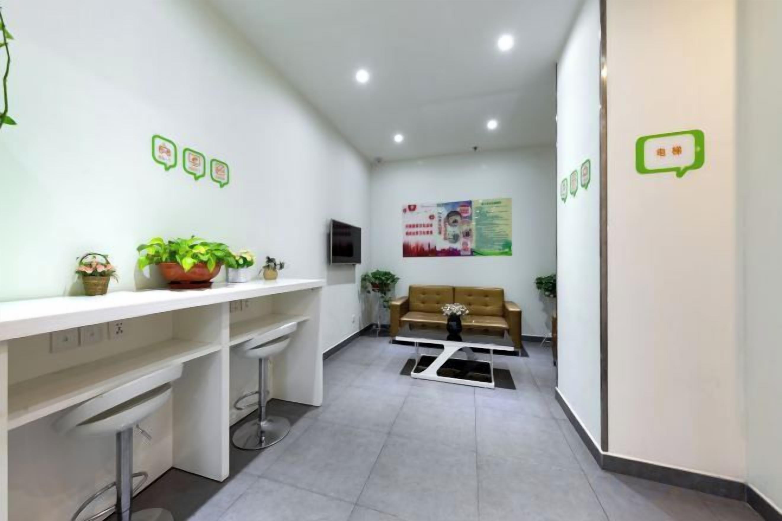 Un área de recepción con un mostrador blanco, un sofá y un televisor montado en la pared.