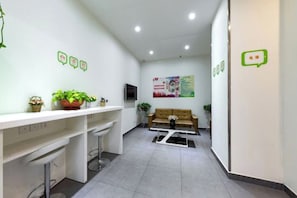 Un espace d’accueil avec un comptoir de réception blanc, un canapé et un téléviseur fixé au mur.